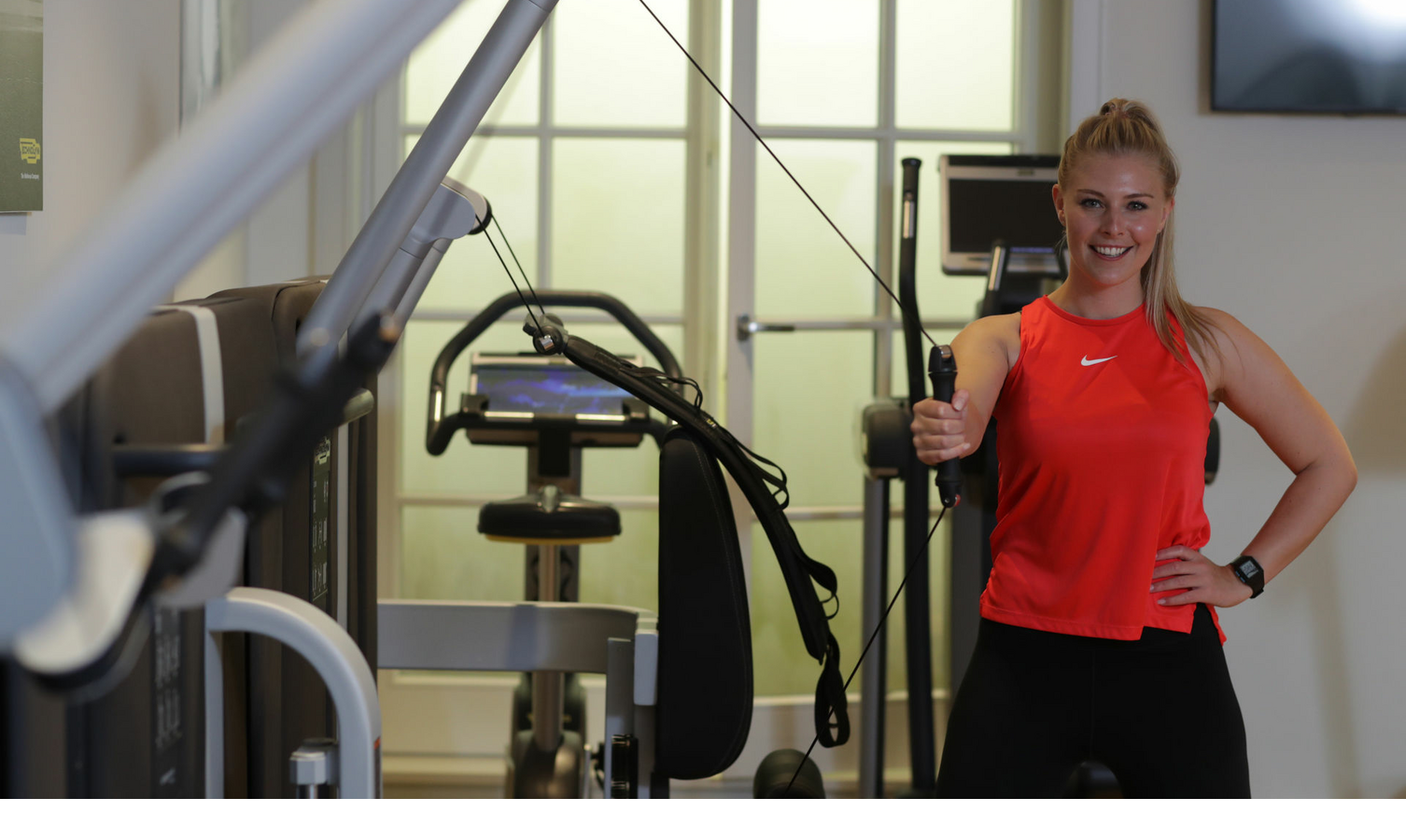 Frau trainiert am Gerät im Fitnessraum