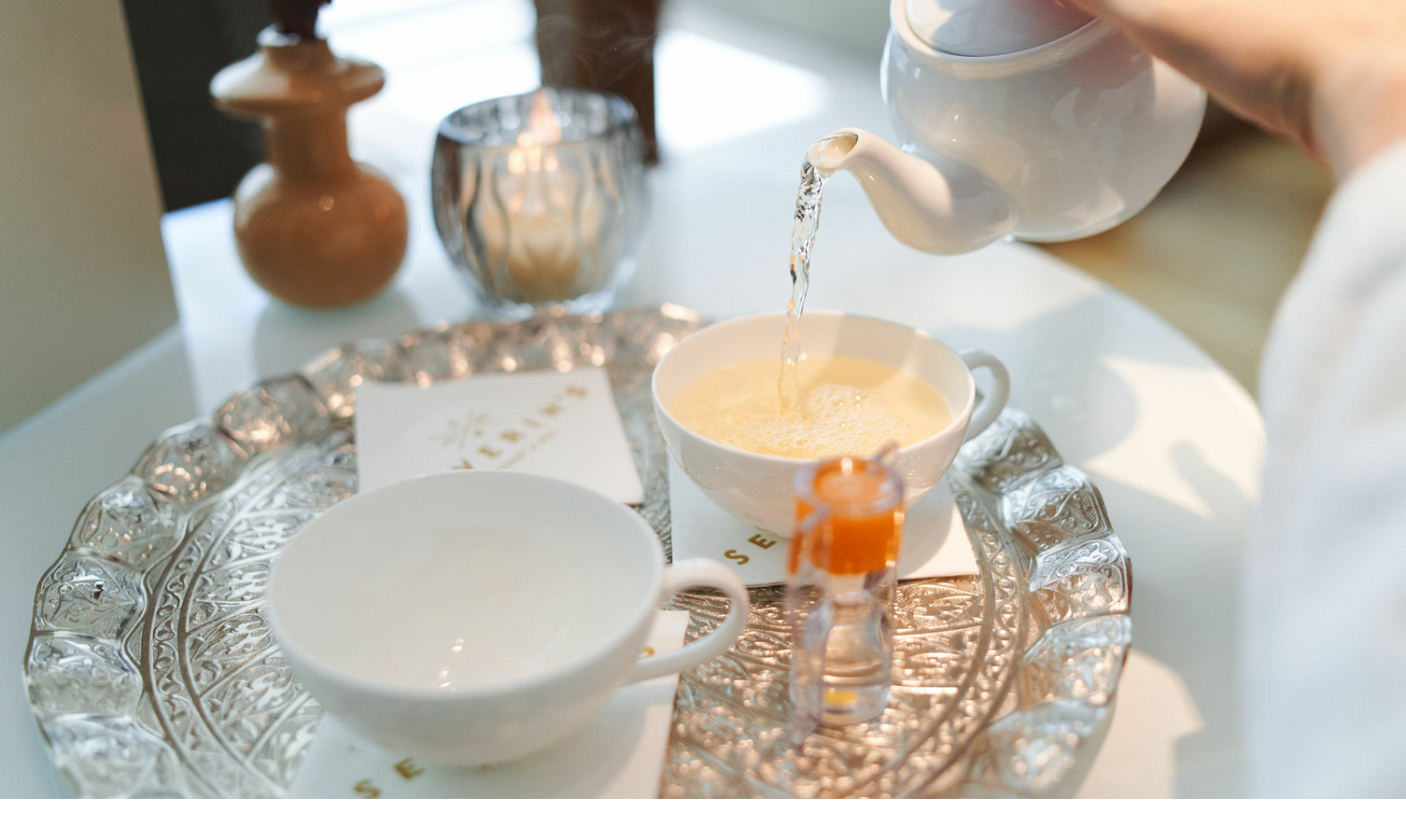 Tee wird in eine Tasse auf einem kunstvollen Tablett im Severin*s Resort & Spa, Sylt, eingeschenkt.