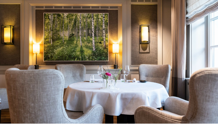 Photographs by artist Andreas Wagner in Tipken's Restaurant by Nils Henkel | Severin*s Resort & Spa Sylt Elegant restaurant with a table setting, comfortable armchairs and a painting of Birkenwald on the wall.