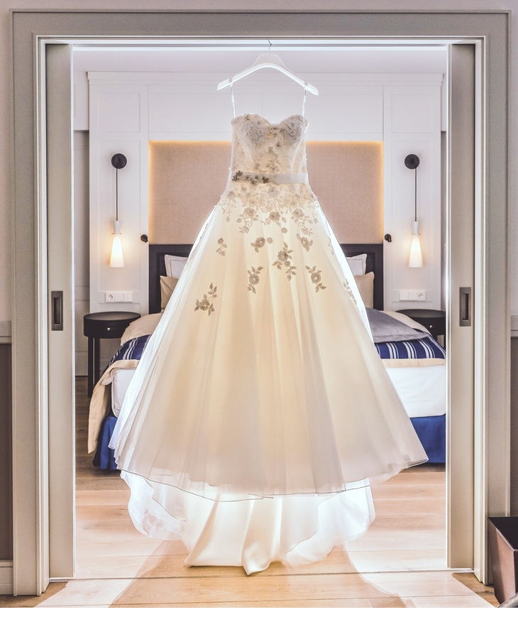 Brautkleid wird vorbereitet für die Braut und Hochzeitszeremonie im Hotel Severin*s auf Sylt Elegant wedding dress hangs in luxurious hotel room with stylish furnishings and soft lighting.