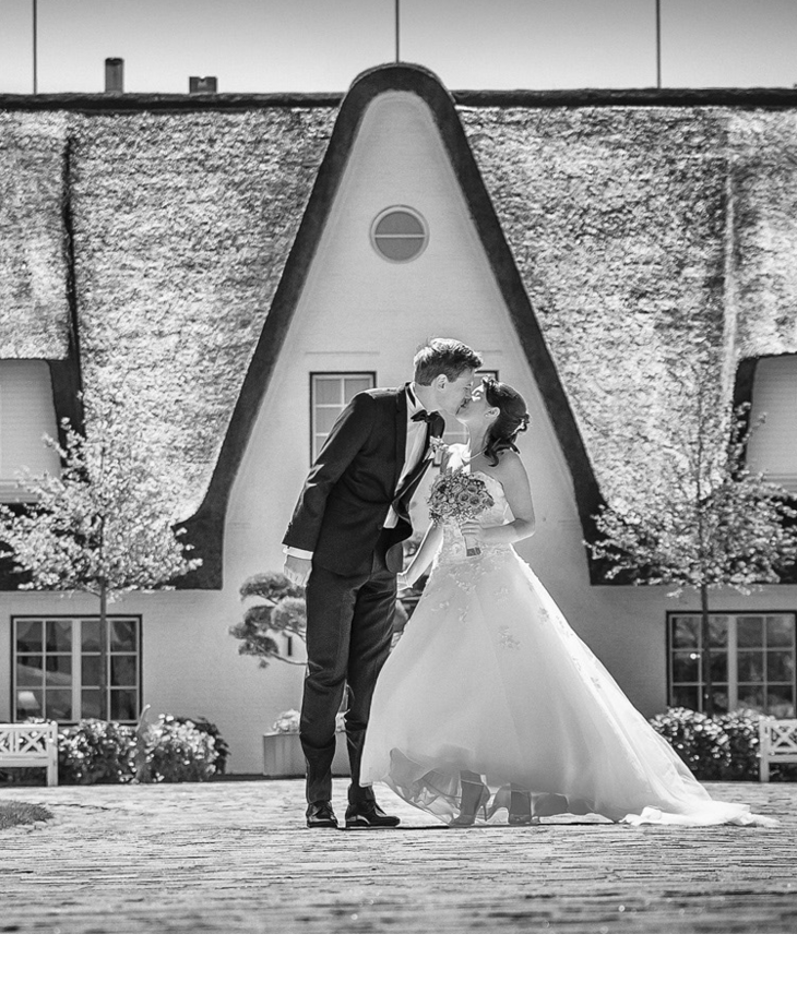 Braut und Bräutigam Kuss vor dem Hauptgebäude des Hotel Severin*s Resort und Spa auf Sylt